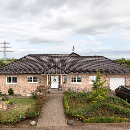 Stilvoller Bungalow mit maronenbraunen Dachziegel auf dem Walmdach