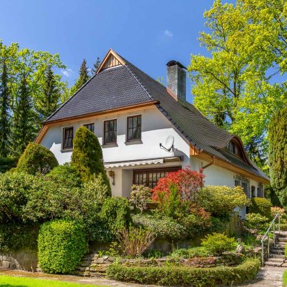 Traditionelles Einfamilienhaus mit Krüppelwalmdach, gedeckt mit Biberschwanzziegel in edelschwarz