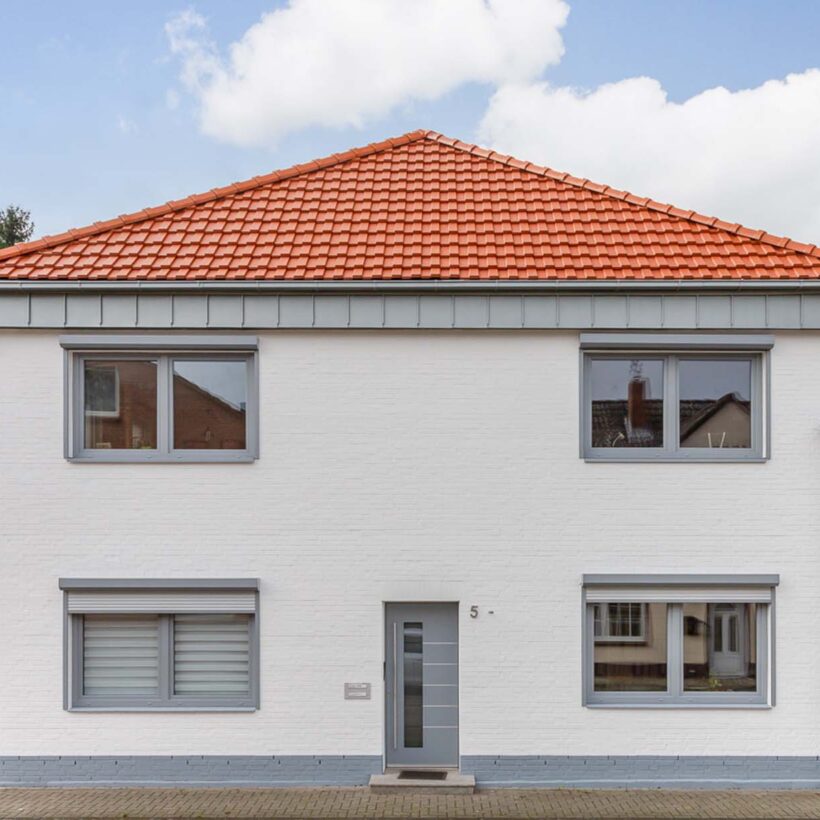 Vooraanzicht van een vrijstaand huis bedekt met moderne dakpan J160 in oudrood